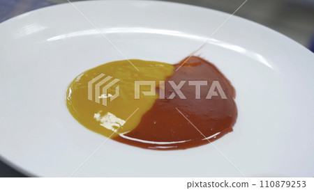 Smearing jam on a plate. Two kinds of jam smeared on the plate with a spatula Smearing jam on a plate. Two kinds of jam smeared on the plate with a spatula 110879253