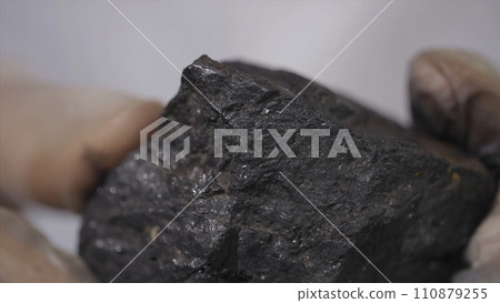 Male hands in gloves holding coal. Scientist with a sample of coal. Black coal in miner's hand Male hands in gloves holding coal. Scientist with a sample of coal. Black coal in miner's hand 110879255