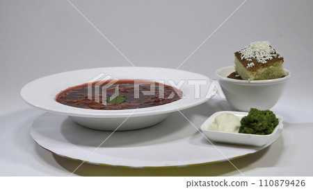 Red Borsch with meat in plate. A delicious red borscht with sour cream and herbs on a white plate. Traditional Ukrainian beetroot soup - red borsch and dumplings with garlic 110879426