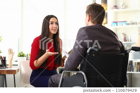 Woman office offers man on wheelchair prosthetics 110879429
