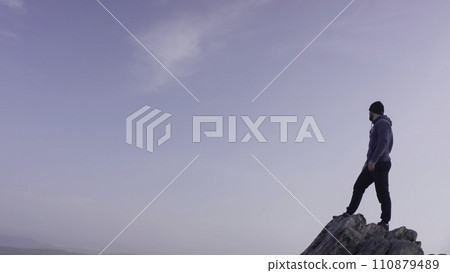 Man on top of the mountain. A young, athletic man stands on a high rock Man on top of the mountain. A young, athletic man stands on a high rock 110879489