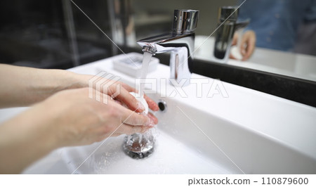 Man thoroughly washes his hands with soap under tap Man thoroughly washes his hands with soap under tap 110879600