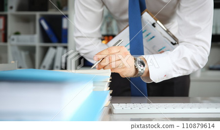 Man in tie makes notes on documents on table Man in tie makes notes on documents on table 110879614