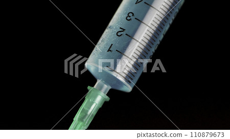 Taking vaccine into a glass syringe from a ampule on a black background. Closeup. Syringe is typed in turquoise fluid injection from illness serious illnesses, the concept of medicine 110879673