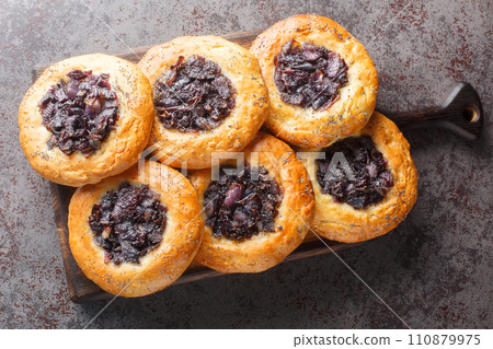 Cebularz is a wheat dough pancake in Polish and Jewish cuisine topped with diced onion and poppy seed close-up on a wooden board. Horizontal top view 110879975