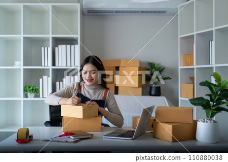 Young woman working online ecommerce shopping at her shop. Young woman sell prepare parcel box of product for deliver to customer. Online selling, ecommerce. Selling products online 110880038