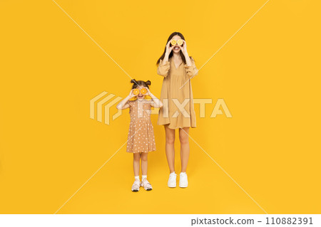 Mother and daughter are playing, on a yellow background. 110882391