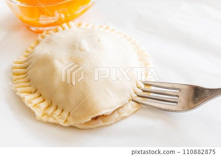 Making a pie by wrapping the ingredients in the dough and sealing it with a fork 110882875