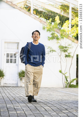 一個 50 多歲的微笑男子肩上背著背包走路 110883313