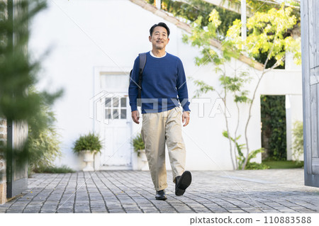 一個 50 多歲的微笑男子肩上背著背包走路 一個 50 多歲的微笑男子肩上背著背包走路 110883588