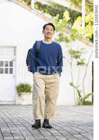 一個50多歲的男人微笑著,肩上背著背包 一個50多歲的男人微笑著,肩上背著背包 110883642