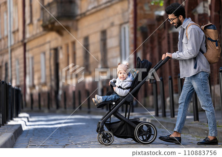 Dark-haired tall man with a baby carriage in the city street 110883756