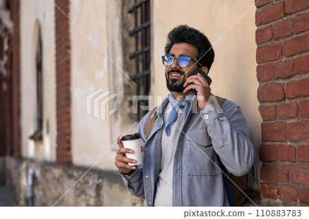 Smiling dark-haired man talking on the phone 110883783