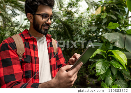 Hindu man with tablet in hands in botanical garden 110883852