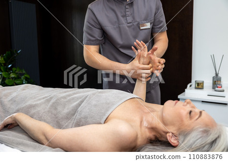 Male massage therapist doing hand massage to a female client Male massage therapist doing hand massage to a female client 110883876