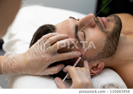 Dark-haired bearded man having session of mesotherapy in a beauty salon 110883956