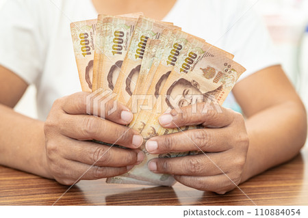 Asian business woman holding Thai banknote currency money. 110884054