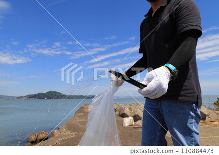 一名男子在海灘上撿垃圾 一名男子在海灘上撿垃圾 110884473