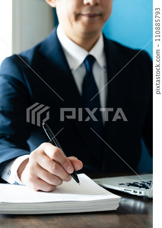 Businessman taking notes in front of a computer Businessman taking notes in front of a computer 110885793