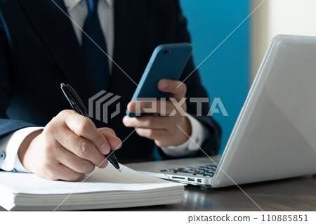 一位商人的手看著他的智慧型手機並做筆記 110885851