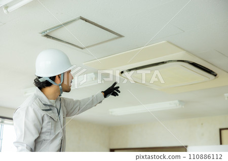一名穿著工作服的男子正在檢查閣樓 一名穿著工作服的男子正在檢查閣樓 110886112