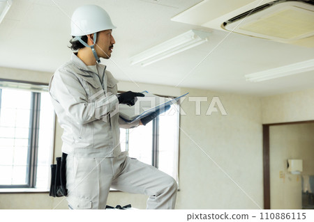 一名穿著工作服的男子正在檢查閣樓 一名穿著工作服的男子正在檢查閣樓 110886115