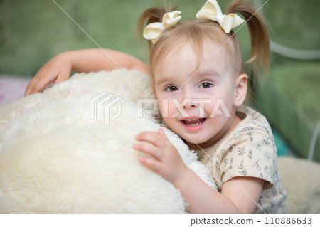 Little girl posing with a fluffy toy at home. 110886633