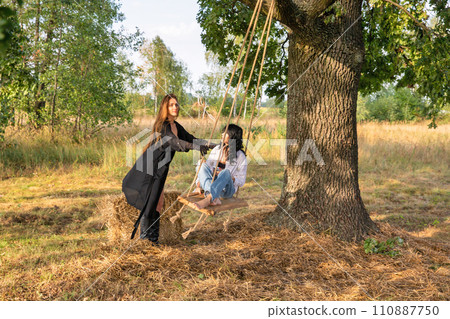 Beautiful caucasian young women on a wooden swing. 110887750