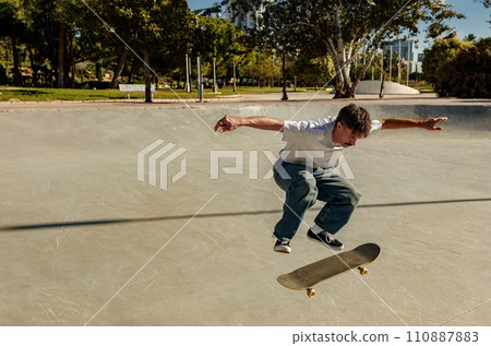 Active young man riding skateboard in skate park on sunny day. Extreme sport concept Active young man riding skateboard in skate park on sunny day. Extreme sport concept 110887883