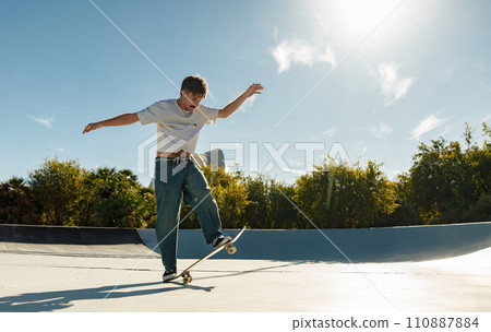 A young man doing tricks on his skateboard at the skate park. Active sport concept A young man doing tricks on his skateboard at the skate park. Active sport concept 110887884