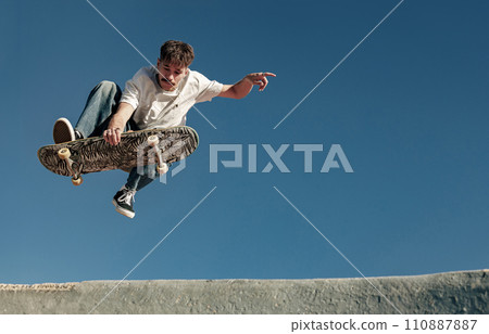 A young man doing tricks in the air on his skateboard at the skate park. Active sport concept 110887887