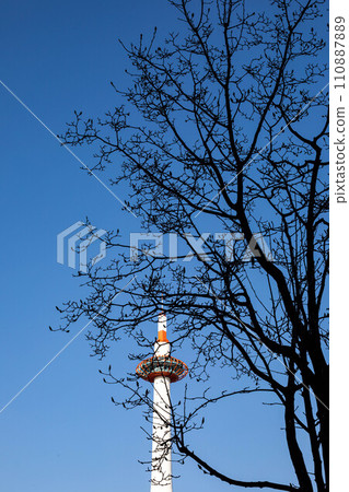 Spring in front of Kyoto Station, silhouette of Kyoto Tower and trees rising against the blue sky Spring in front of Kyoto Station, silhouette of Kyoto Tower and trees rising against the blue sky 110887889