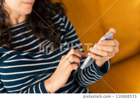 girl sits on the sofa and writes a chat message on a smartphone 110888533