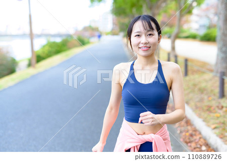 年輕女性行走、身體化妝、飲食、跑步服、運動胸罩 年輕女性行走、身體化妝、飲食、跑步服、運動胸罩 110889726