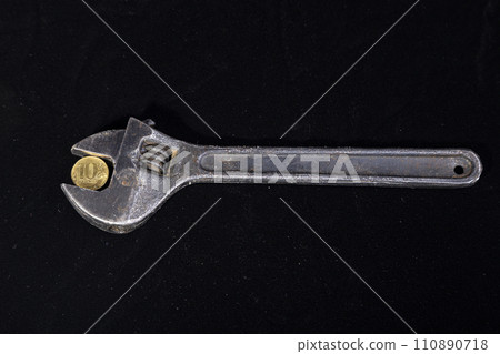 Allegory of the global financial crisis - Iron 10 rubles coin (written ten rubles, Bank of Russia in the Russian) in the grip of economic crisis, on a black background. Finance and business concept 110890718