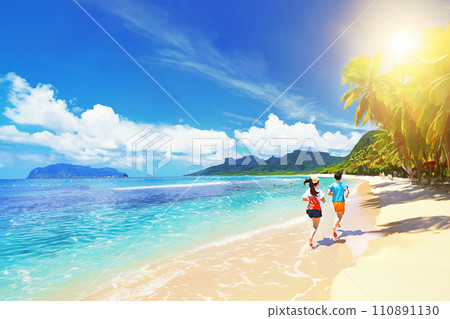 People running along the beach side of a southern island under the blue sky 110891130