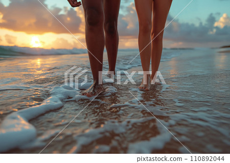 legs of a couple walking along the beach in the surf 110892044