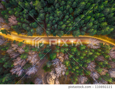 Aerial view of road in beautiful autumn forest at sunset. Beautiful landscape with empty rural road, trees with red and orange leaves. Aerial view of road in beautiful autumn forest at sunset. Beautiful landscape with empty rural road, trees with red and orange leaves. 110892221