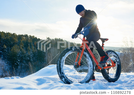 Serious hipster cyclist preparing for extreme rice in winter forest 110892278