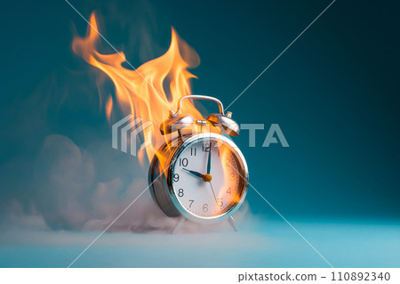 Burning alarm clock. Time out or deadline pressure concept. Clock on fire, symbol of hot sale, discounts, shopping time, countdown. Oversleep, waste of time, insomnia. Time is ending, running out. 110892340