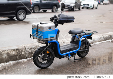 An electric scooter for cargo transportation with a front and rear trunk. Modern urban transportation An electric scooter for cargo transportation with a front and rear trunk. Modern urban transportation 110892424