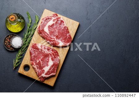 Raw ribeye steaks with savory spices 110892447