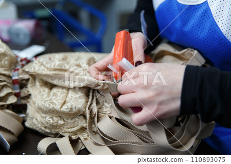 Close up hands of worker at clothing company labelling their product. Close up hands of worker at clothing company labelling their product. 110893075