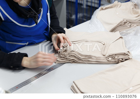 Close up hands of worker at clothing company labelling their product. 110893076