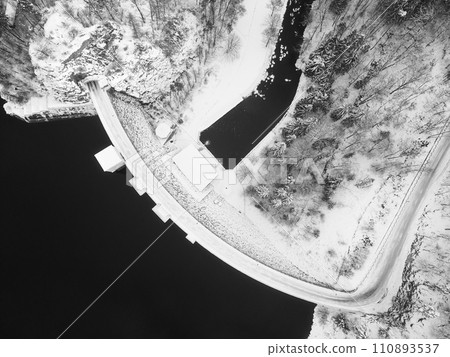 Sec water reservoir with concrete dam and wintertime snowy hills of Iron Mountains around. Czechia. Aerial view from drone.. Black and white image. 110893537