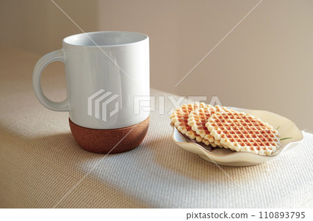 Coffee and Italian waffles in a white mug with a cork bottom on a white sofa 110893795