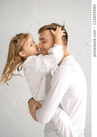 The daughter gently kisses Dad on the nose. A child in strong male hands. Father's Day 110893889