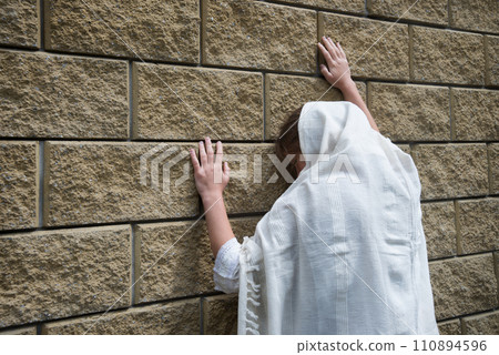 Praying person at the wall 110894596