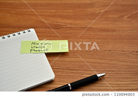 A sticky note that says Minimum Viable Product is attached to a notepad. A sticky note that says Minimum Viable Product is attached to a notepad. 110894803