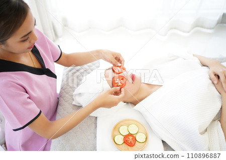 Masseuse masking face with tomato and spa face woman treatment and massage aroma therapy Masseuse masking face with tomato and spa face woman treatment and massage aroma therapy 110896887